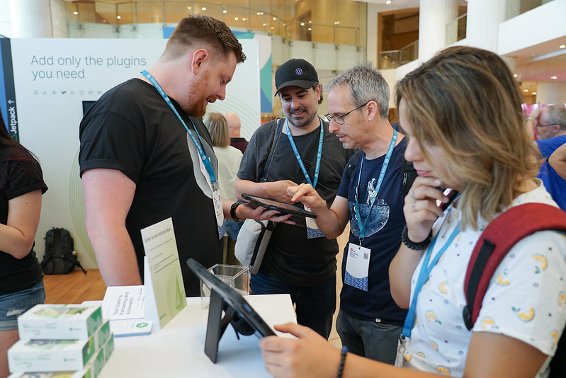 People at a WordCamp Europe Sponsor's stand